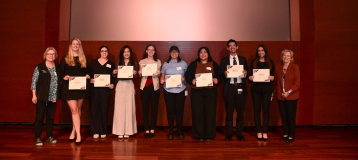 Group of people standing on stage holding award certificates