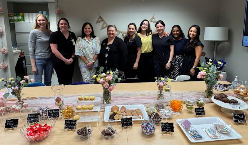 Group of women pose behind table full of desserts