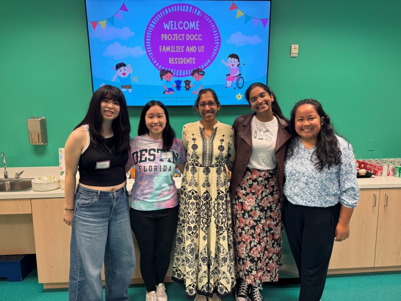 Group of five women smiling in front of TV monitor