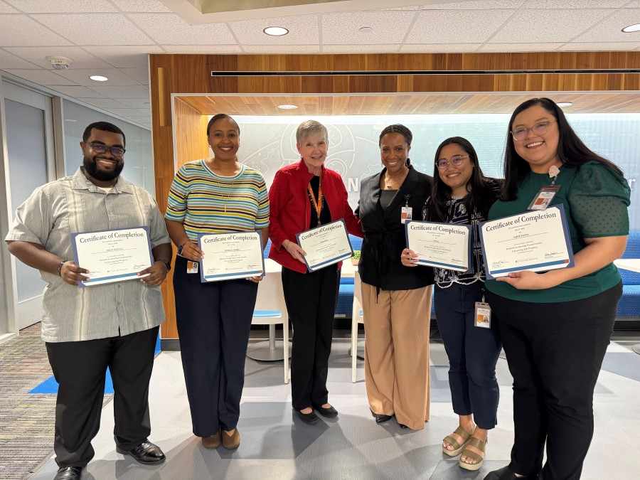 Six people smiling and holding paper certificates