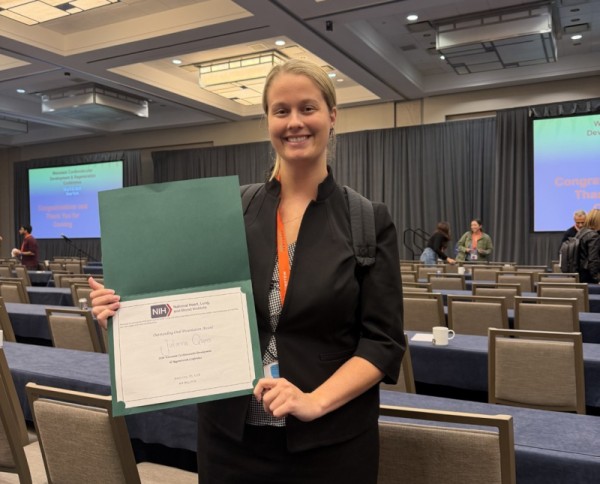 Julianna Quinn holding award in conference room