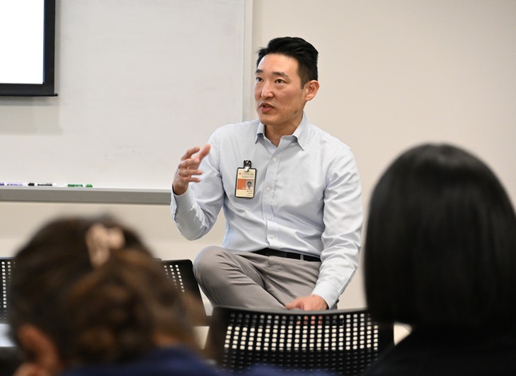 Man sitting on desktop giving a lecture