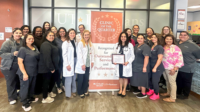 Group of providers at UT Physicians clinic around banner