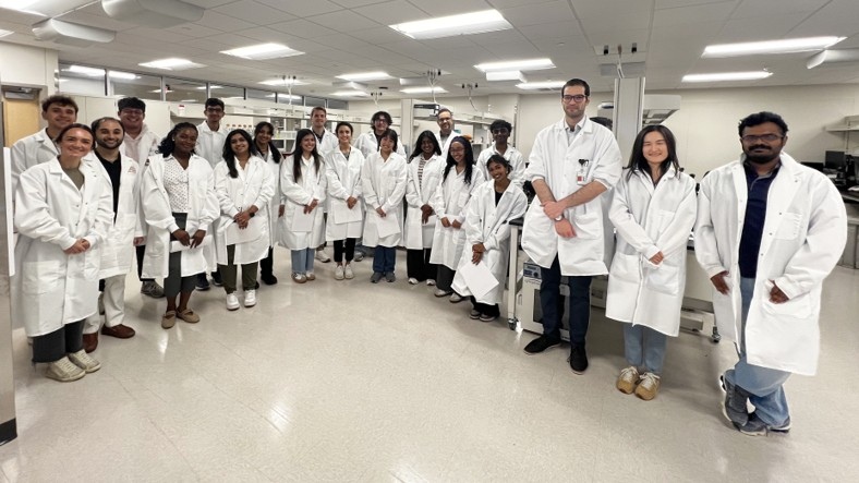 CiCHD scholars, faculty, and trainees in white coats in the lab