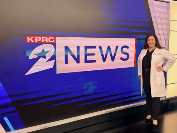 Dr. Ruggiero stands in front of news logo