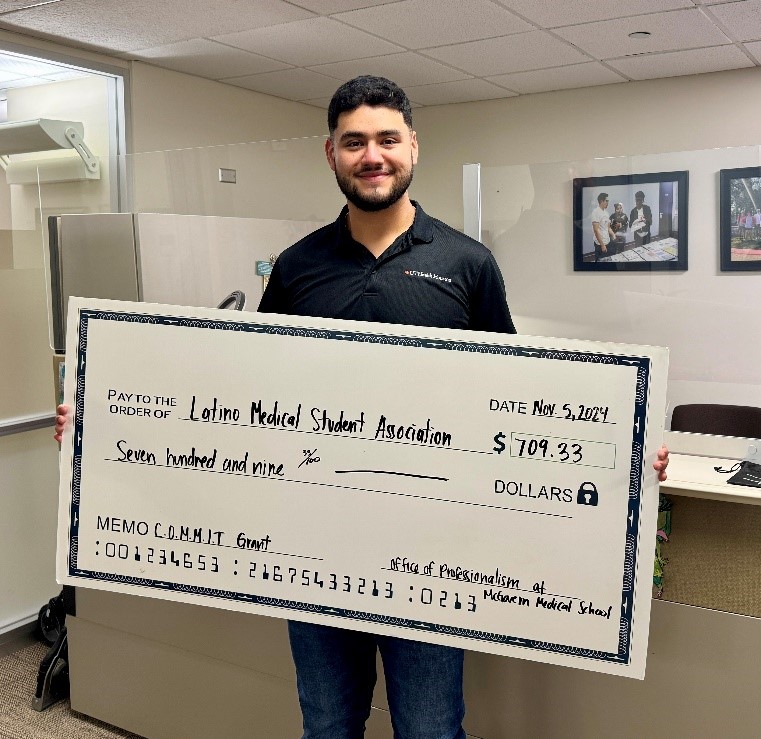 Latino Medical Student Association student holding up check with amount they were granted from winning the COMMIT Grant.