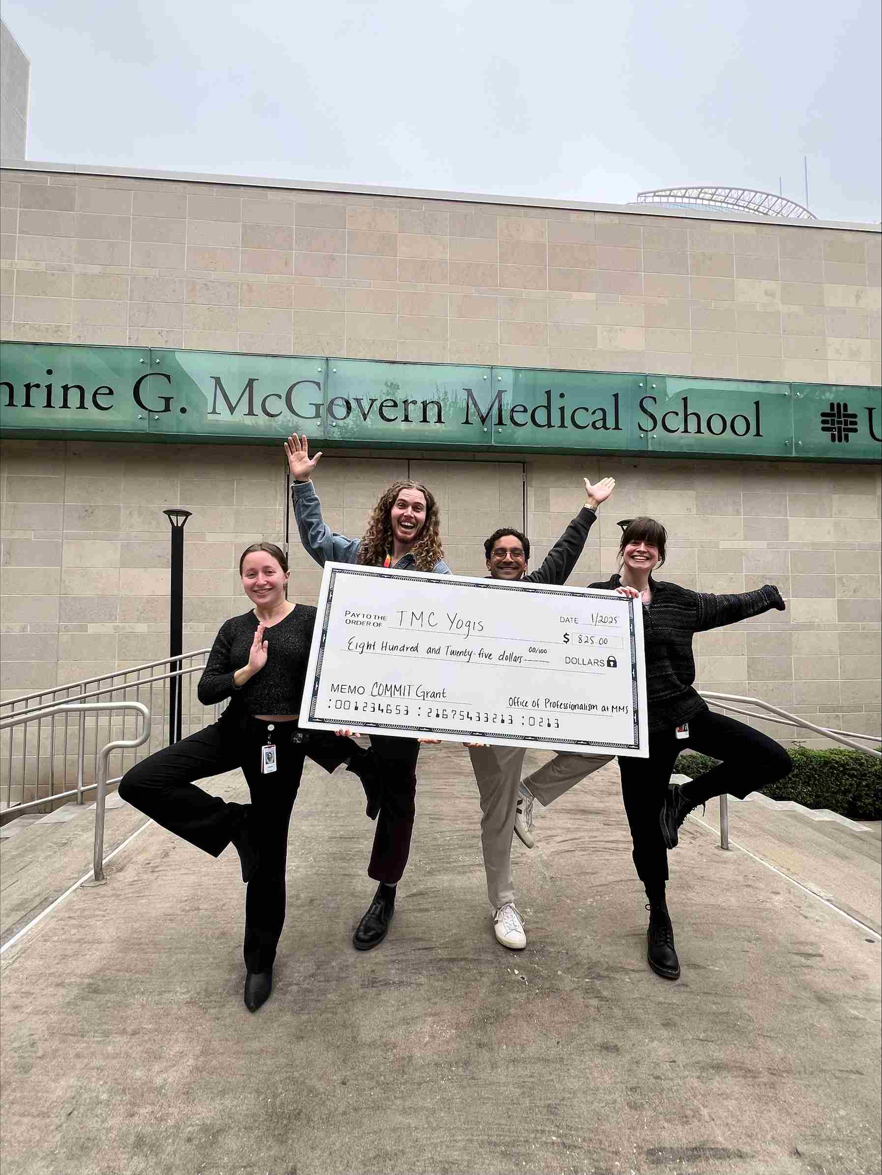 TMC Yogis, student organization, holding up a check with amount they were granted.