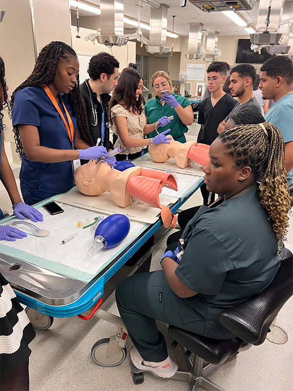 Students practicing airway management techniques on medical mannequins.