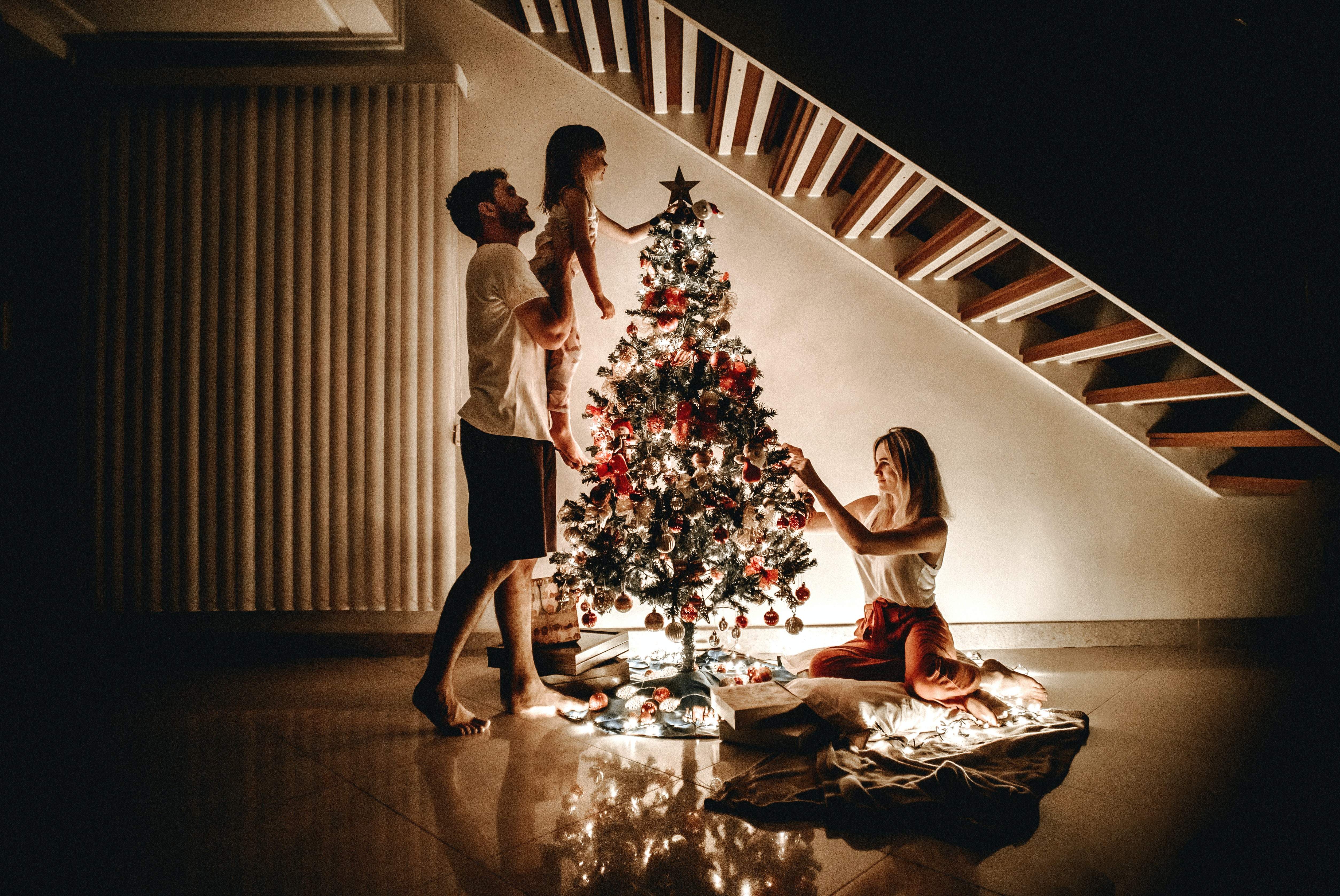 Друзья украшают елку. Наряжаем елку. Люди наряжают елку. Семья наряжает елку. Люди у новогодней елки.