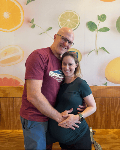 A picture with a couple, man is holding pregnant wife's stomach.