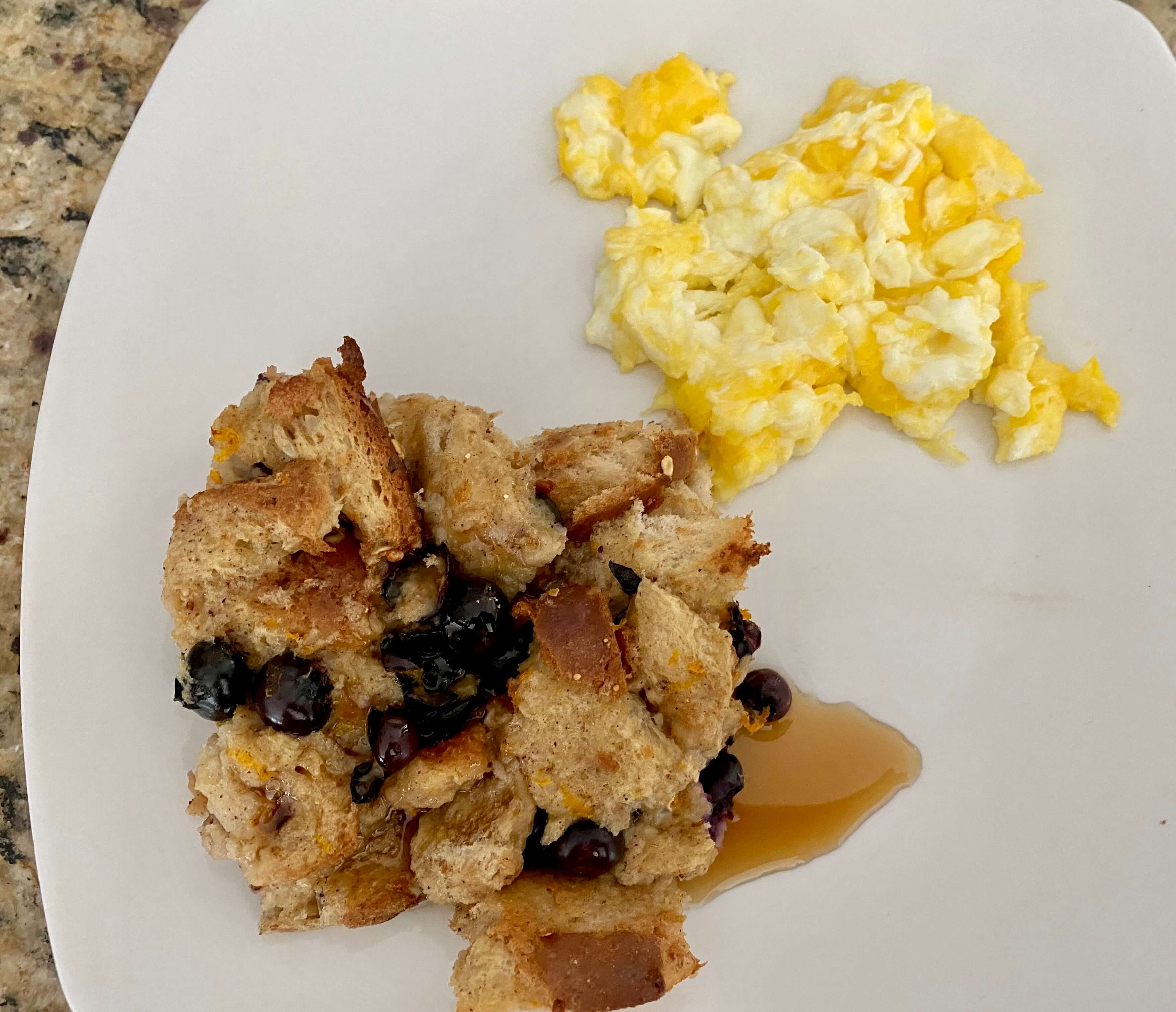 Blueberry orange french toast casserole and scrambled eggs on white plate