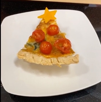 Slice of quiche decorated like a tree on a white plate