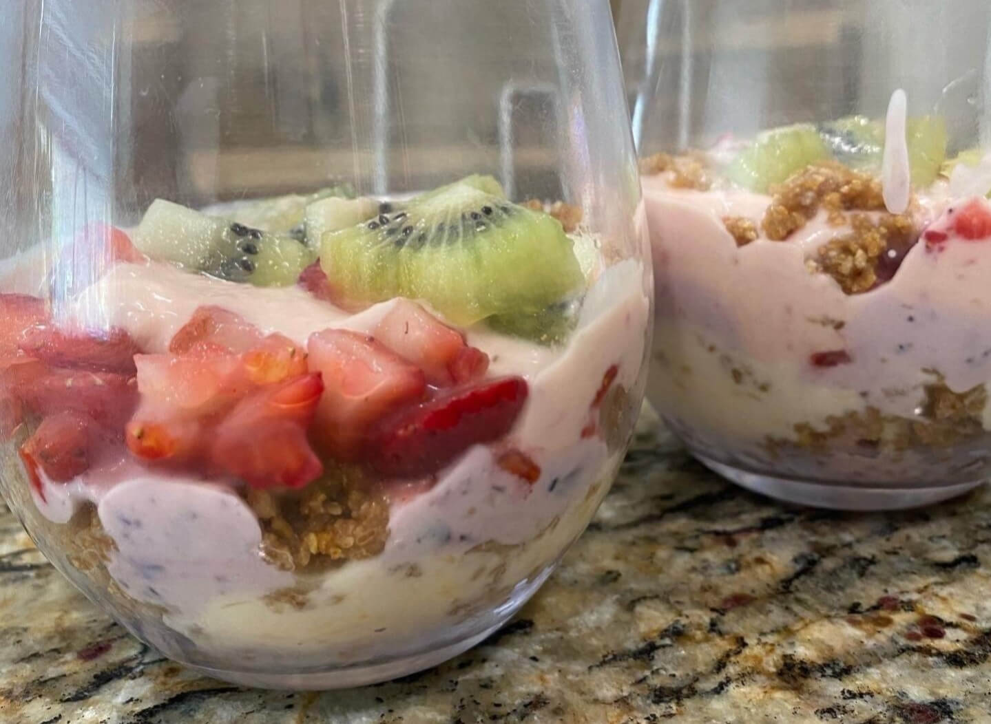 Two fruit 'n' cereal rainbow yogurt parfaits with strawberry and kiwi