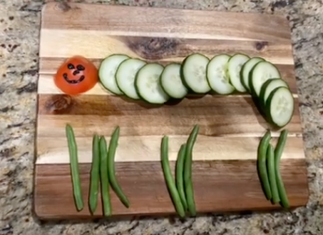 Caterpillar veggie bug that uses cucumber slices for the body, green beans for the legs, and a slice of tomato for the head