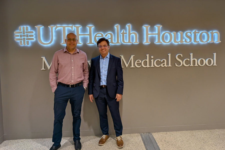 Dr. Shervin Assassi and Dr. Harry Karmouty-Quintana pose for a photo in front of a glowing McGovern Medical School at UTHealth Houston sign in the medical school.