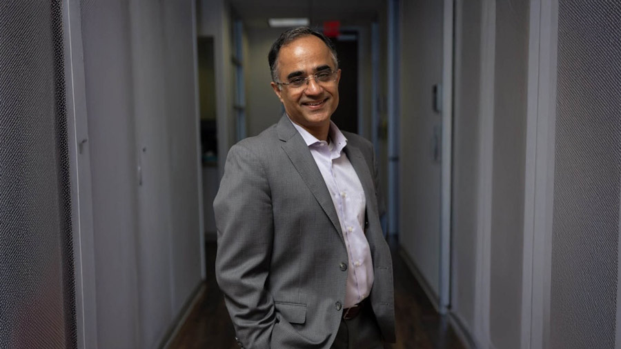 Dr. Nitin Tandon in a gray suit standing in a hallway