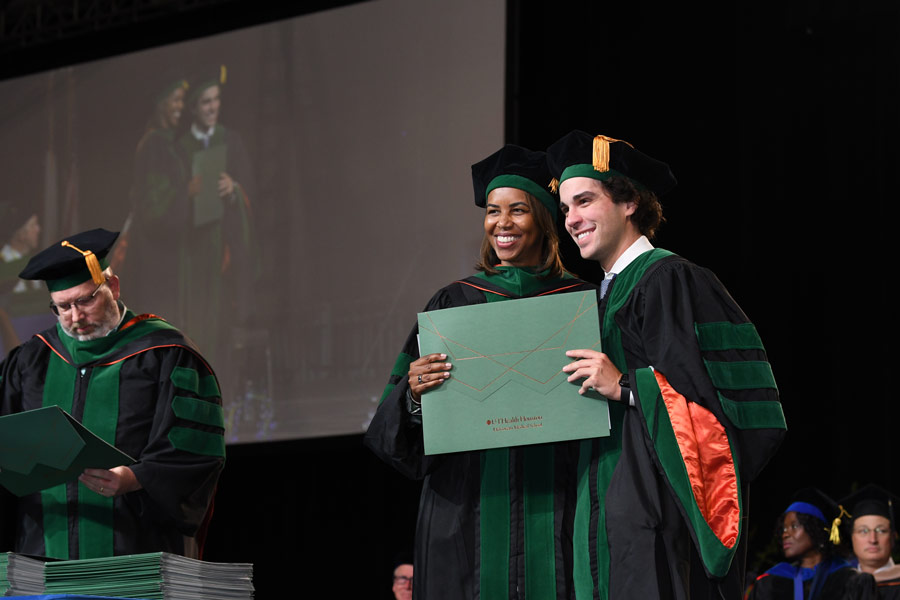 A graduate smiles while posing for a photo with LaTanya J. Love, MD, after receiving a diploma.