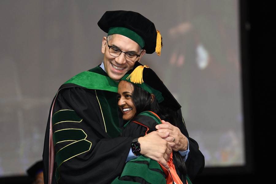 A graduate embraces a family member on stage following the McGovern Medical School Class of 2026 Commencement Ceremony.