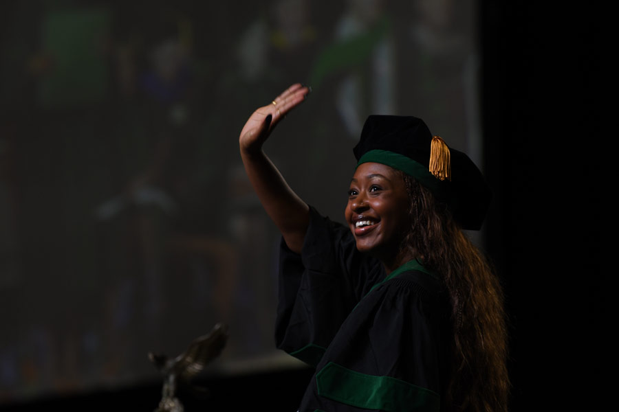A graduate waves from the commencement stage during the McGovern Medical School Class of 2026 Commencement Ceremony.