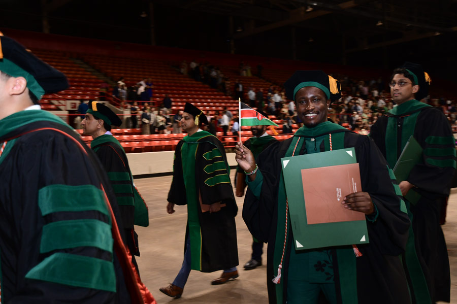 A graduate waves a flag while walking with classmates following the McGovern Medical School Class of 2026 Commencement Ceremony.