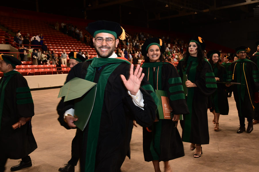 A graduate waves while walking with fellow graduates during the McGovern Medical School Class of 2026 Commencement Ceremony.