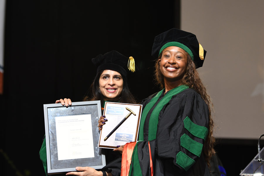 A graduate poses with an award and certificate during the McGovern Medical School Class of 2026 Commencement Ceremony.