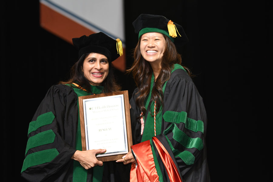 A graduate smiles while posing with a faculty member after receiving an award during the McGovern Medical School Class of 2026 Commencement Ceremony.