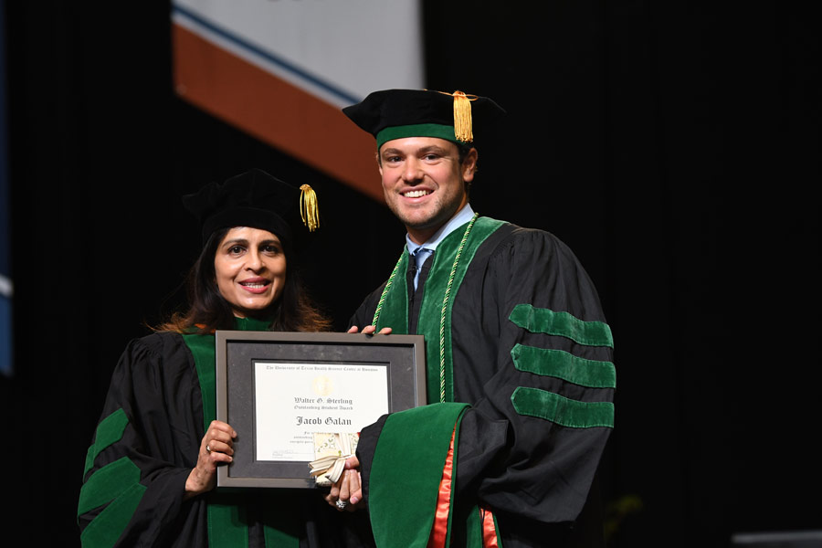 A graduate poses with a faculty member after receiving an academic award during the McGovern Medical School Class of 2026 Commencement Ceremony.