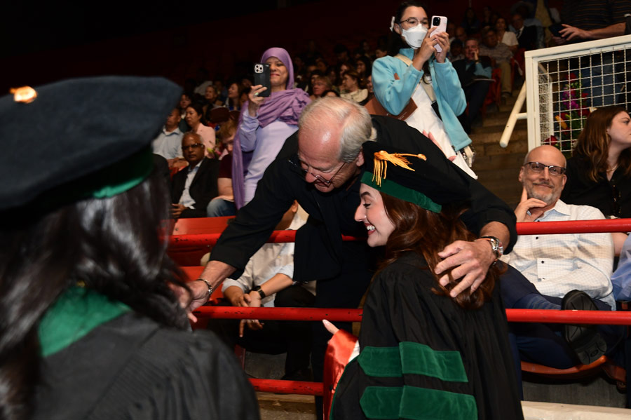 man congratulating two graduates