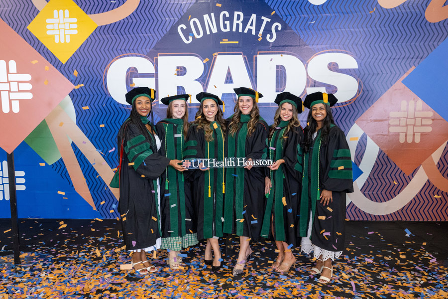 McGovern Medical School students celebrate commencement with confetti and a sign reading UTHealth Houston