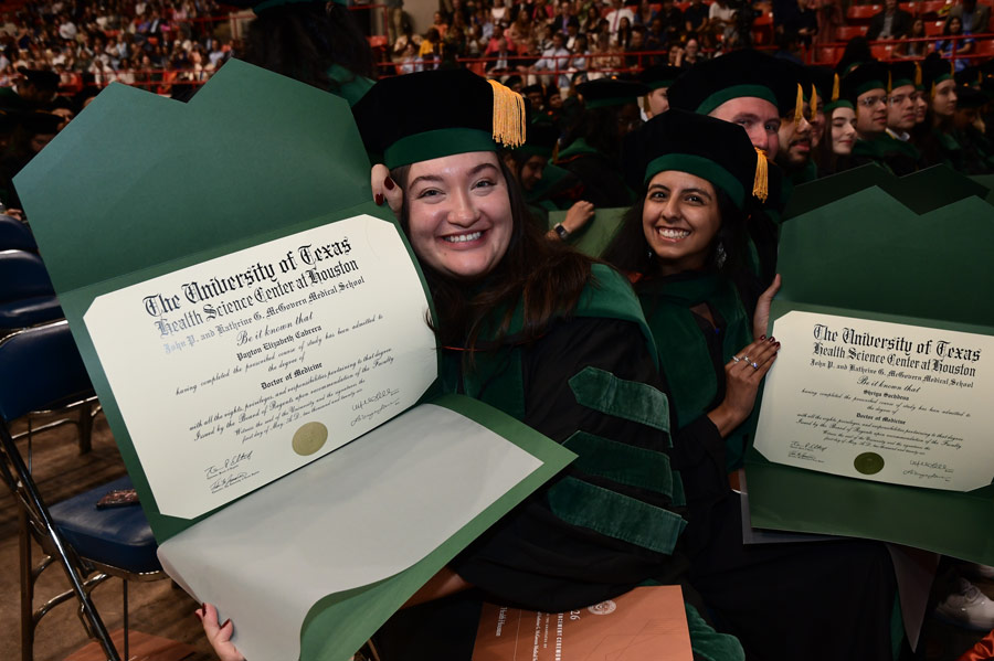 Students from the McGovern Medical School Class of 2026, dressed in green and black commencement regalia, show off their diplomas during the commencement ceremony.