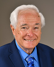 Dr. Charles Ericsson in a black suit with a blue tie and blue button up shirt