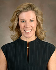 Dr. Deborah Horn smiles in a professional headshot while wearing a dark sleeveless dress and pearl necklace against a neutral background.