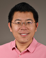Dr. Xiangsheng Huang poses for a headshot in a pink button up shirt