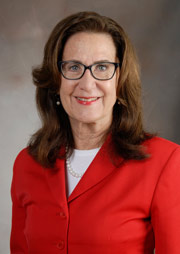 Dr. Claire E. Hulsebosch poses for a headshot in a red blazer with white shirt