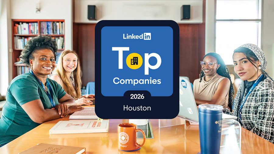 Four employees sit around a conference table in a collaborative workspace, with a graphic in the center announcing LinkedIn Top Companies 2026 Houston. Laptops, notebooks, and coffee mugs are visible on the table as the group looks toward the camera.