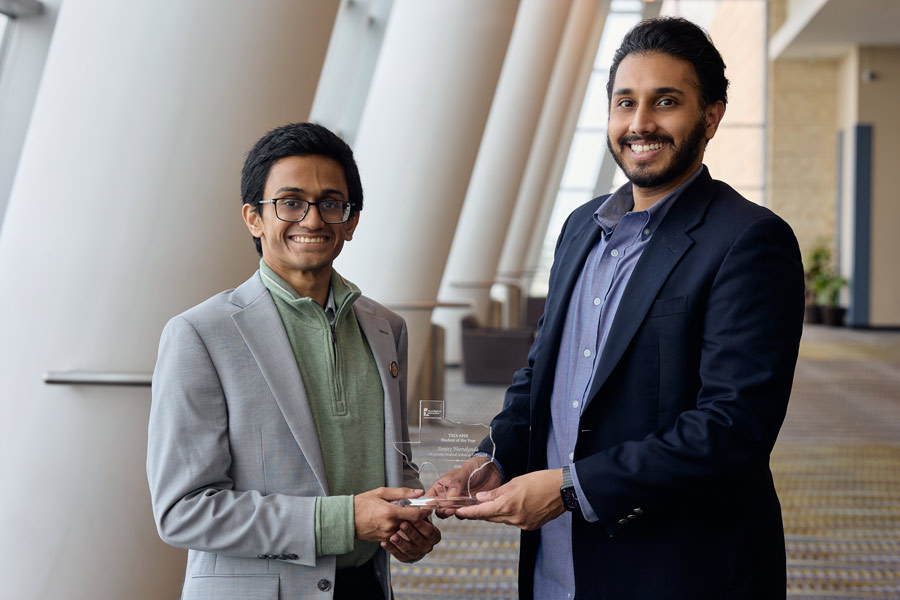 Two medical students smile while holding a Texas-shaped “Student of the Year” award during a recognition event for the Texas Medical Association.