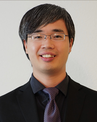 Dr. Michael Zhu poses for a headshot with a black button up shirt and purple tie