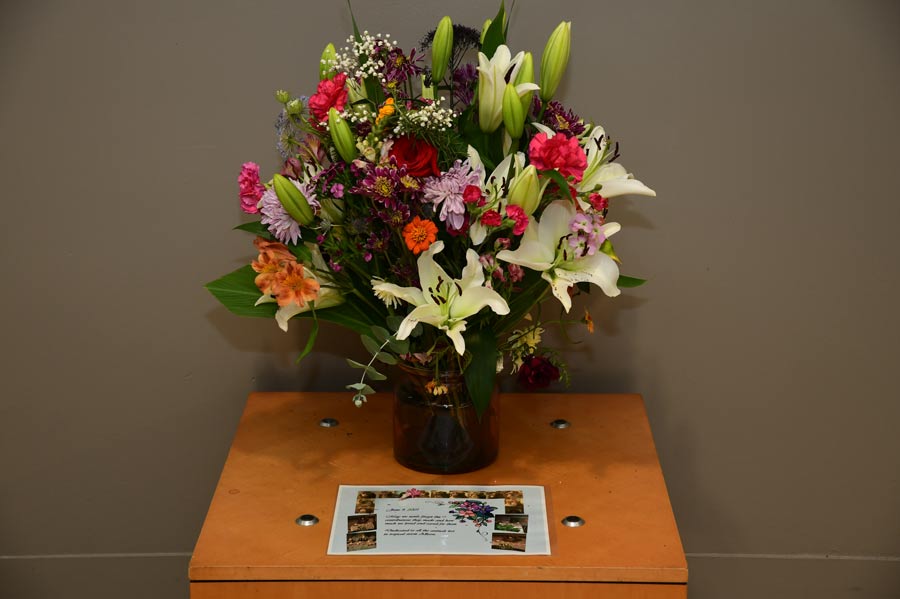 Close-up of a memorial floral arrangement and tribute display honoring those lost during Tropical Storm Allison, placed inside McGovern Medical School.