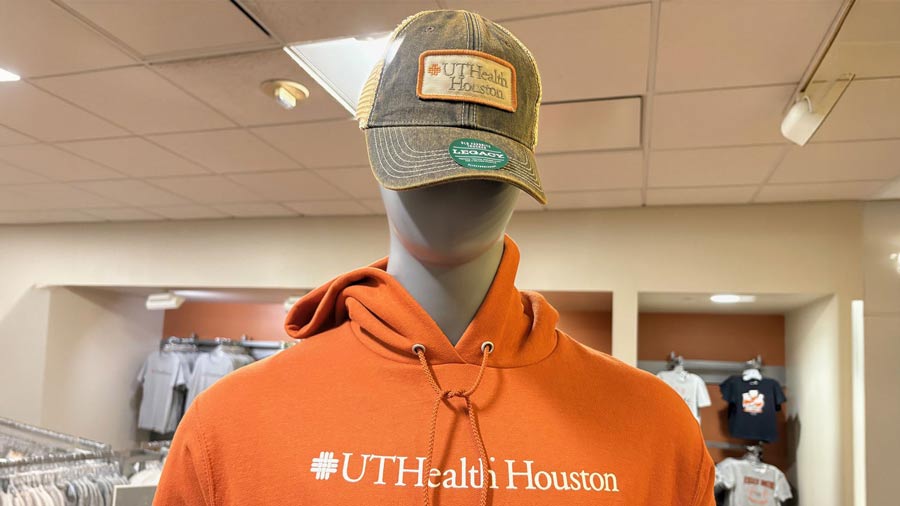 Mannequin wearing an orange UTHealth Houston hoodie and a UTHealth Houston baseball cap in a campus bookstore.