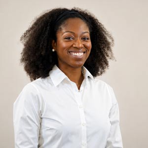 Dr. Asia Bright poses for a headshot in a white button up shirt in front of a cream colored background