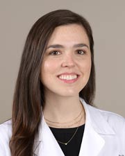 Dr. Lauren Mellor-Crummy poses for a professional headshot in her white lab coat in front of a gray background