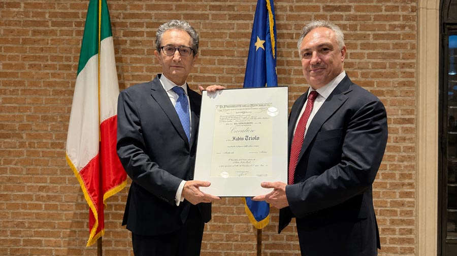 Dr. Fabio Triolo receives the Knight of the Order of Merit of the Italian Republic insignia and certificate of honor from the Consul General of Italy in Houston during a formal ceremony, holding the framed recognition together.