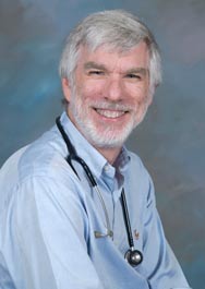 Dr. Robert Yetman poses for a professional headshot in a blue button up shirt with a stethoscope around his neck