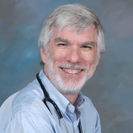 Dr. Robert Yetman poses for a professional headshot in a blue button up shirt with a stethoscope around his neck