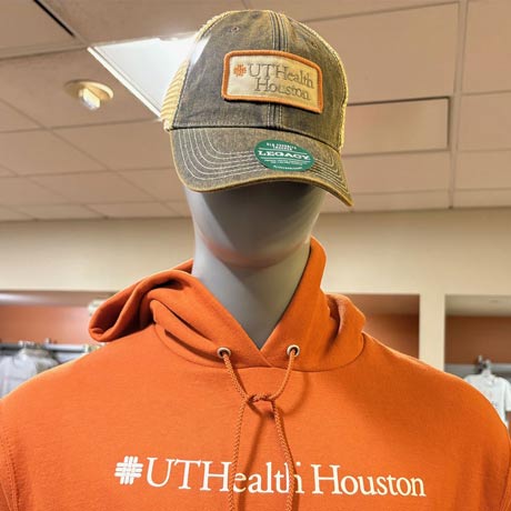 Mannequin wearing an orange UTHealth Houston hoodie and a UTHealth Houston baseball cap in a campus bookstore.