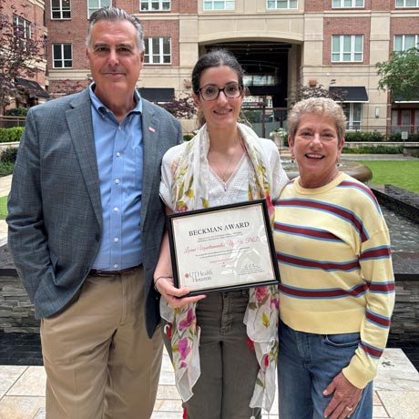Dr. Kevin Morano, left, stands with inaugural Leslie Beckman Award recipient Lierni Ugartemendia, PhD, center, and Leslie Beckman, right, during an outdoor recognition ceremony. Ugartemendia holds her Beckman Award certificate, which honors exceptional service and dedication to the postdoctoral community at UTHealth Houston.