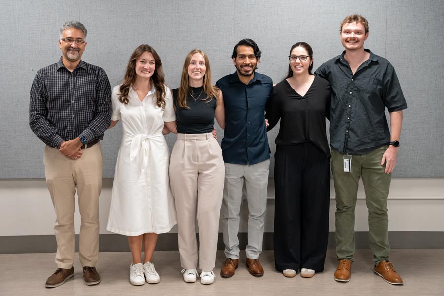 The winners of the 2026 Dean's Research Awards pose for a group photo in front of a gray wall.