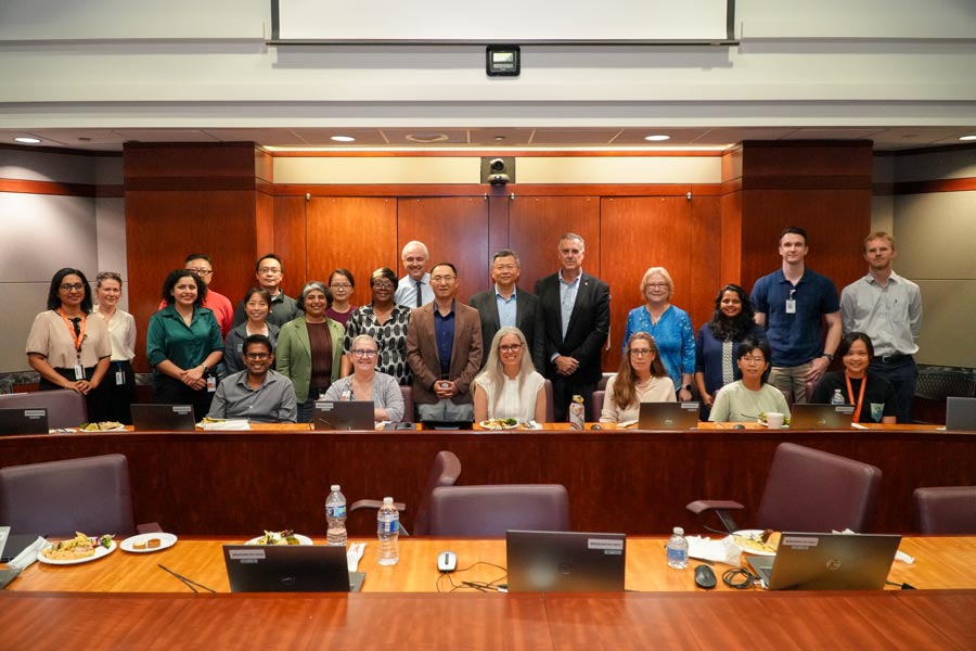 Graduates of the Grants 102 program pose for a photo with program leadership and their faculty mentors in a business conference room.