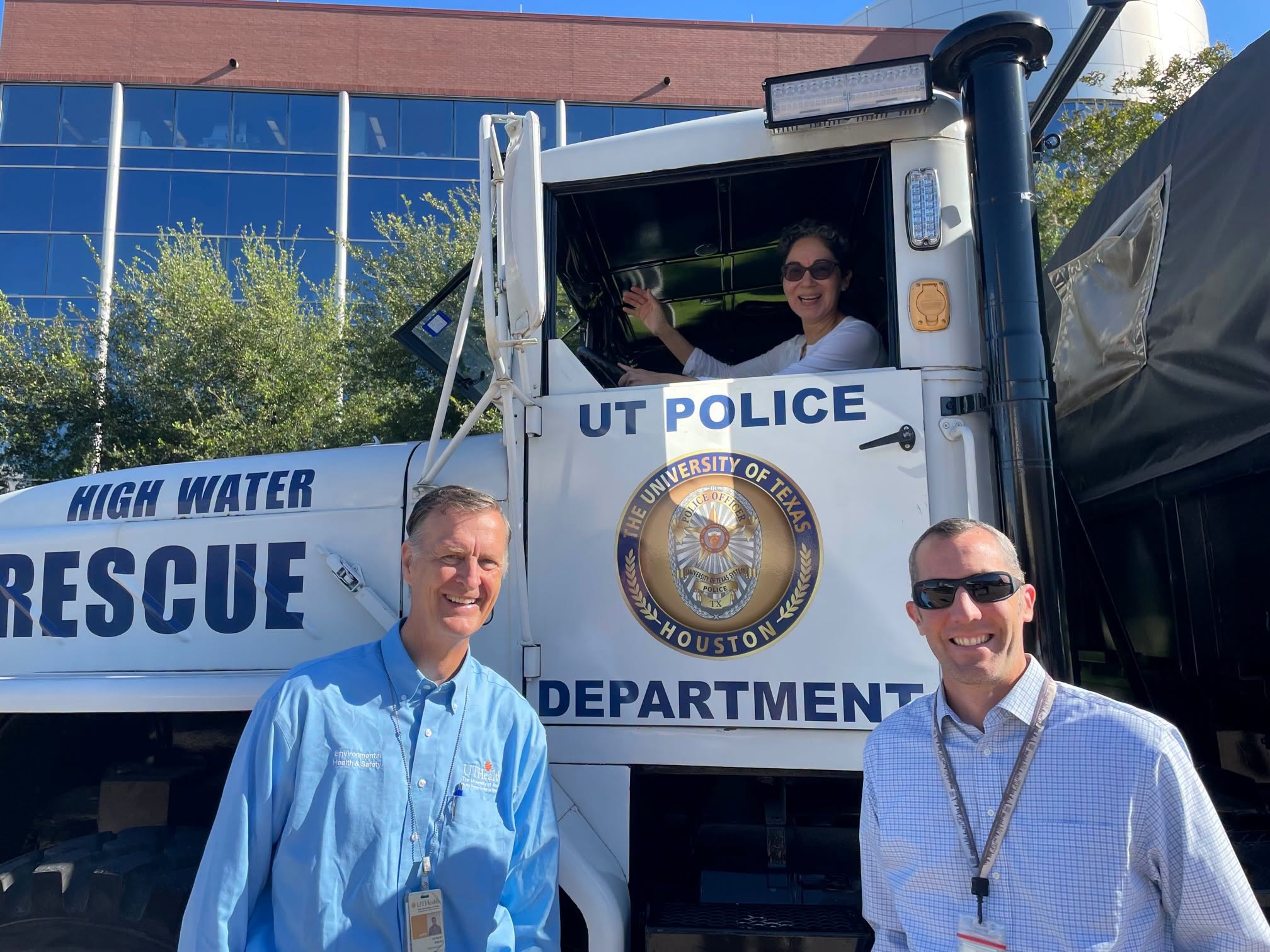 Three UTHealth Houston employees pose with one of the UT Police Department's high-water rescue vehicles. Two stand in front of the truck while another waves from the driver's seat. The truck is marked "High Water Rescue" and displays the UT Police Department seal.